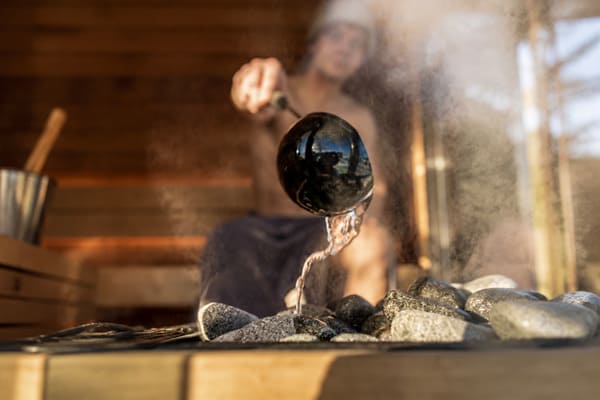 Water being ladled over hot stones creating soft löyly steam
